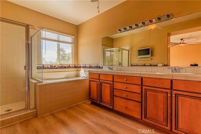 bathroom featuring a garden tub, a sink, wood finished floors, a ceiling fan, and a stall shower