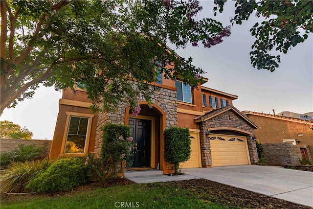 view of front facade with driveway, stone siding, a garage, and stucco siding