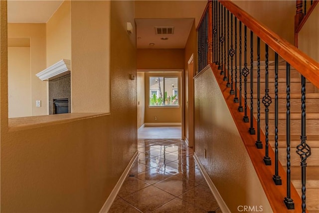 interior space featuring baseboards, visible vents, tile patterned flooring, and a textured wall