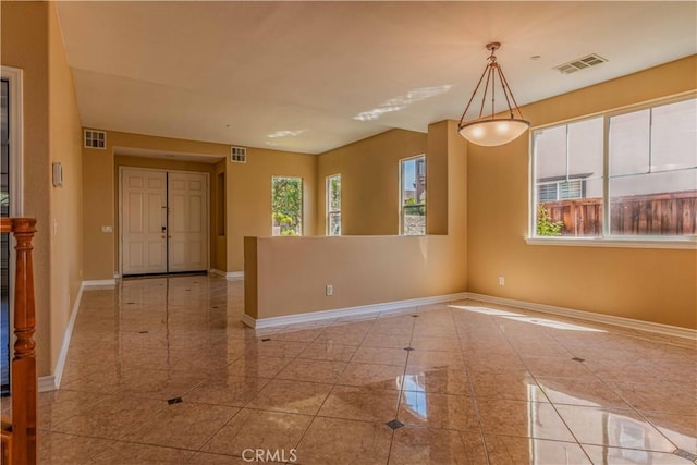 unfurnished room featuring plenty of natural light, visible vents, and baseboards