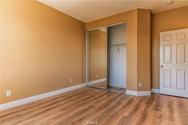 unfurnished bedroom with a closet, baseboards, and wood finished floors