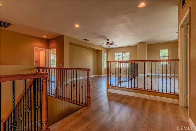 hall featuring baseboards, visible vents, wood finished floors, an upstairs landing, and recessed lighting