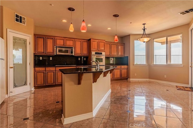 kitchen with appliances with stainless steel finishes, decorative backsplash, visible vents, and brown cabinets