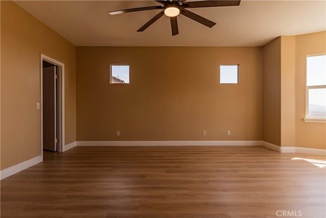 unfurnished room with light wood finished floors, a ceiling fan, and baseboards