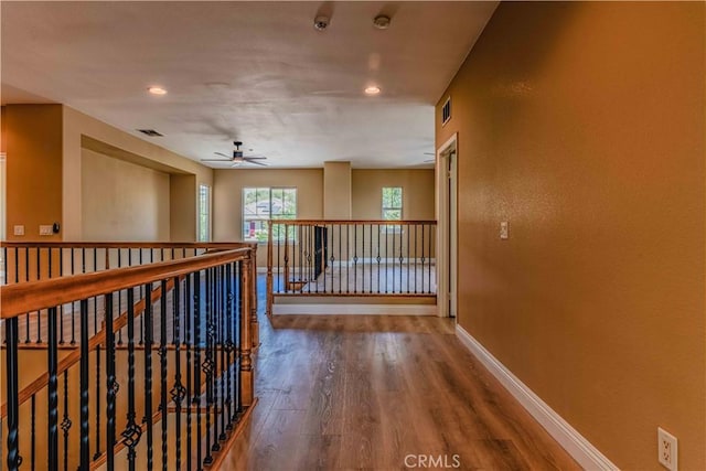 hallway with recessed lighting, wood finished floors, visible vents, and baseboards