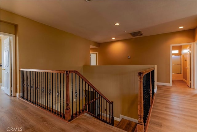 corridor featuring recessed lighting, visible vents, an upstairs landing, wood finished floors, and baseboards