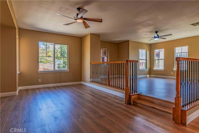 unfurnished room with plenty of natural light, baseboards, and wood finished floors