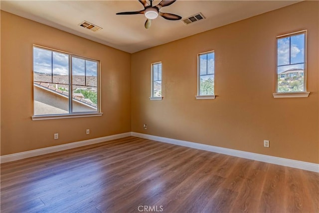 spare room with baseboards, visible vents, ceiling fan, and wood finished floors