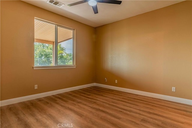 empty room featuring visible vents, ceiling fan, baseboards, and wood finished floors