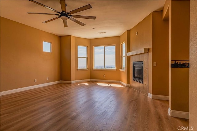 unfurnished living room featuring visible vents, a fireplace, baseboards, and wood finished floors