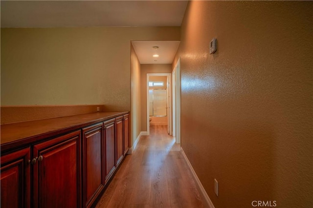 hallway featuring wood finished floors and baseboards