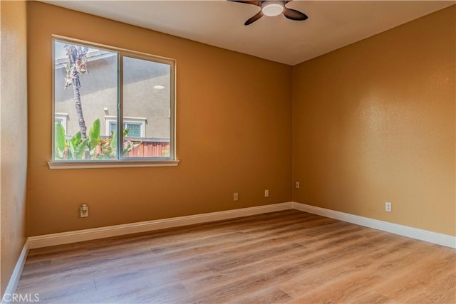 empty room featuring ceiling fan, baseboards, and wood finished floors