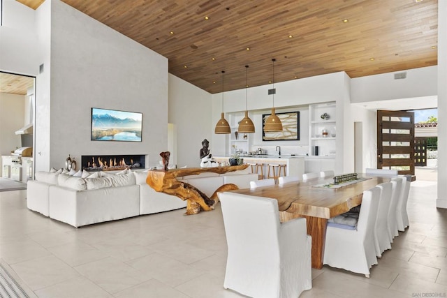 dining space featuring sink, a towering ceiling, and wooden ceiling