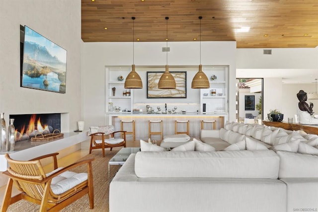 living room with a towering ceiling, built in features, and wooden ceiling