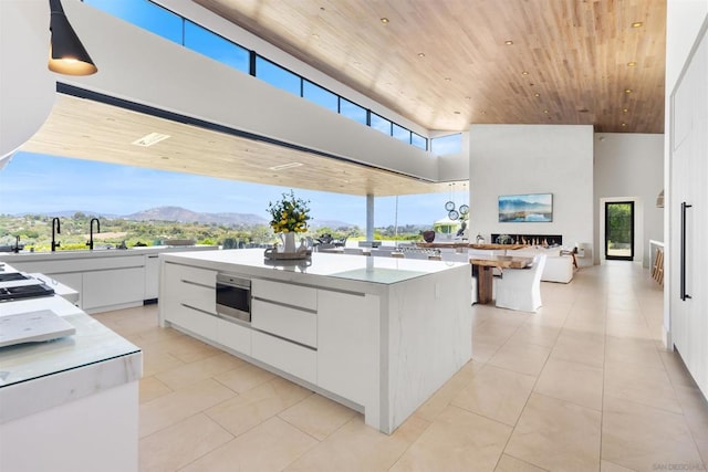 kitchen featuring a towering ceiling, white cabinets, a center island, a mountain view, and wooden ceiling