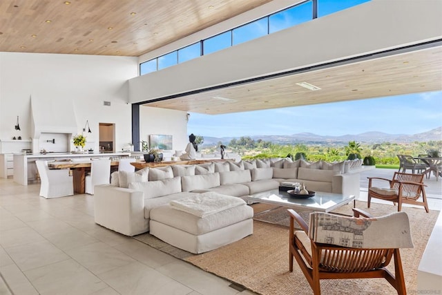 living room featuring a mountain view, a wealth of natural light, wooden ceiling, and a high ceiling