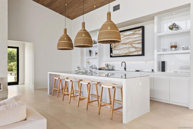 kitchen with built in features, a breakfast bar, white cabinetry, hanging light fixtures, and wooden ceiling