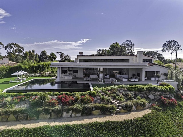 rear view of property with a water view, outdoor lounge area, and a patio area