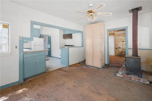 kitchen with white fridge, ceiling fan, and a wood stove