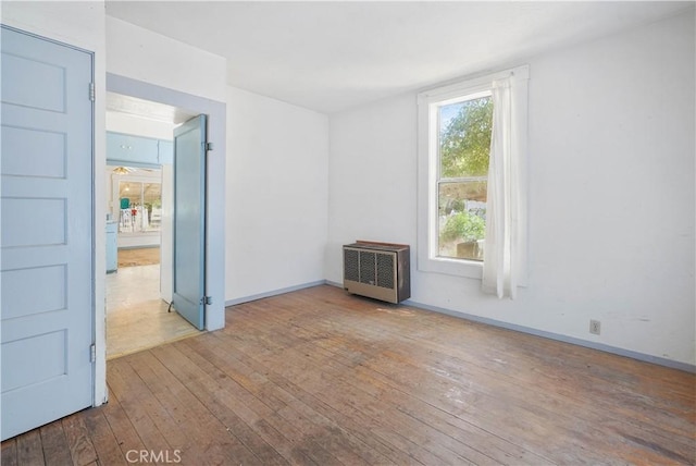 unfurnished room with radiator and light wood-type flooring