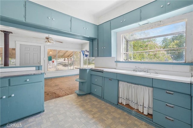 kitchen with blue cabinets, sink, and ceiling fan