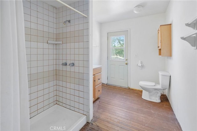 bathroom featuring tiled shower, vanity, toilet, and hardwood / wood-style floors