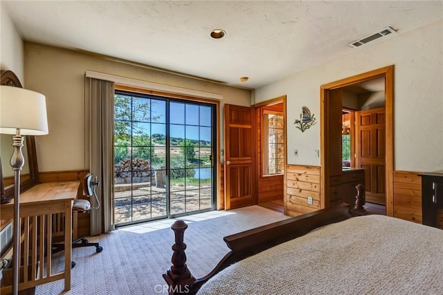 bedroom with access to exterior and wood walls