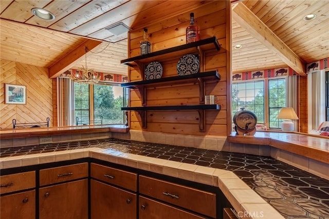 kitchen with tile countertops, lofted ceiling with beams, wooden ceiling, and a wealth of natural light