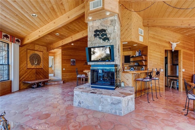 living room featuring lofted ceiling with beams, wood walls, a fireplace, and wooden ceiling