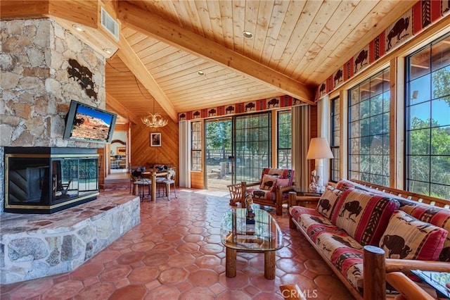 living room featuring vaulted ceiling with beams, a healthy amount of sunlight, and a stone fireplace