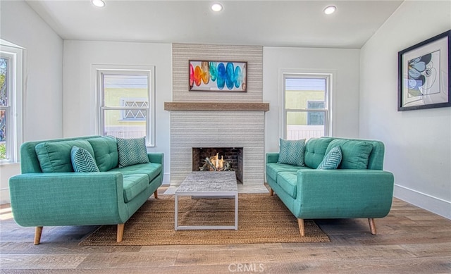 living area featuring wood-type flooring, a large fireplace, and lofted ceiling