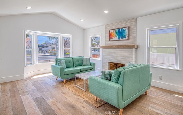 living room with a large fireplace, light hardwood / wood-style flooring, and lofted ceiling