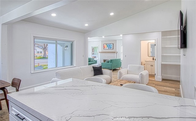 bedroom featuring connected bathroom, light hardwood / wood-style flooring, and lofted ceiling