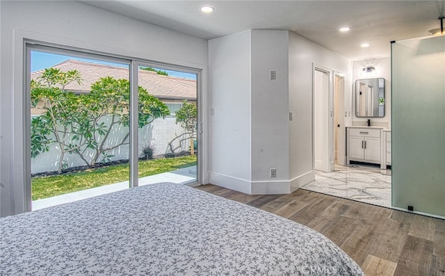 bedroom featuring hardwood / wood-style flooring, access to exterior, connected bathroom, and multiple windows