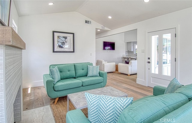 living room with light hardwood / wood-style flooring and vaulted ceiling