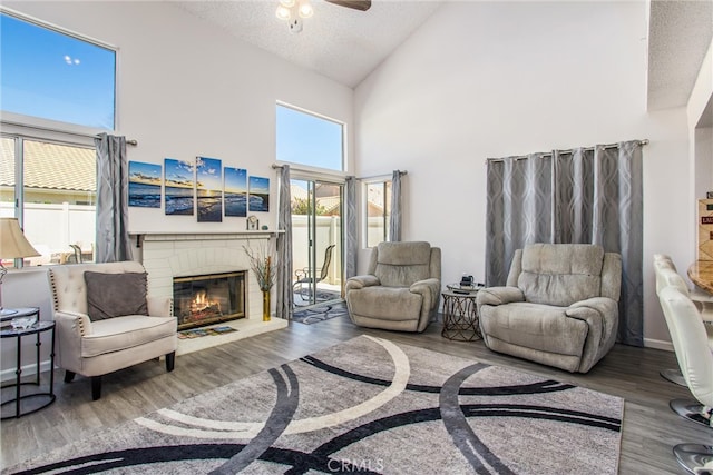 living room featuring a healthy amount of sunlight, ceiling fan, a brick fireplace, and hardwood / wood-style floors