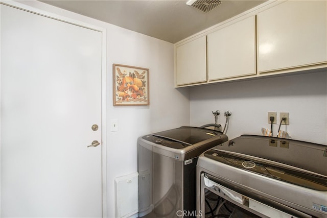 clothes washing area featuring separate washer and dryer and cabinets