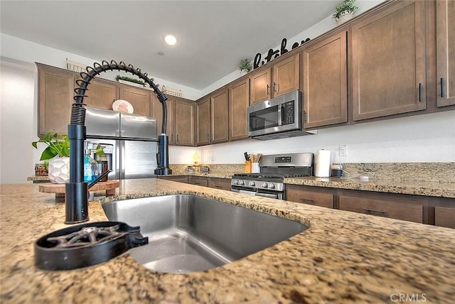 kitchen featuring dark brown cabinetry, stainless steel appliances, and light stone counters