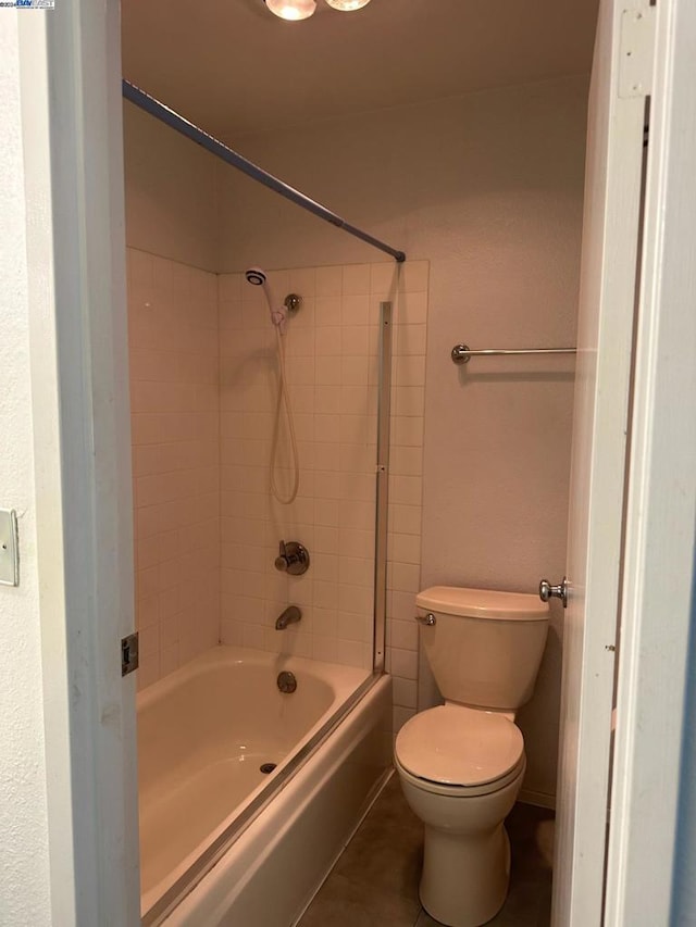 bathroom featuring tiled shower / bath, toilet, and tile patterned flooring