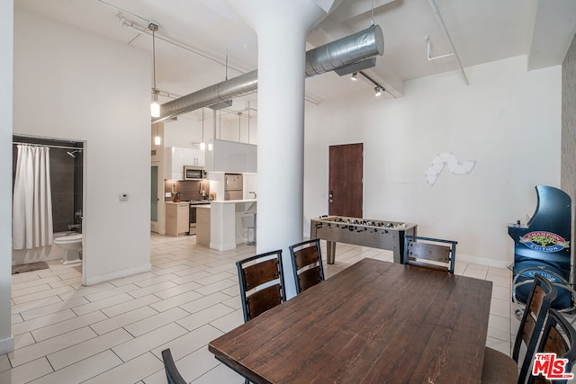 dining space with light tile patterned flooring and a towering ceiling