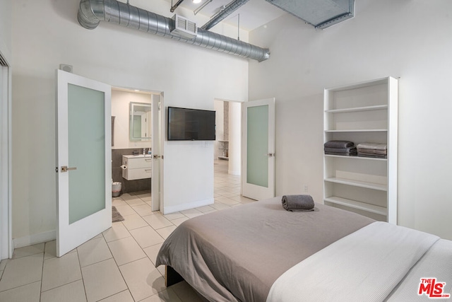 tiled bedroom with a high ceiling and connected bathroom