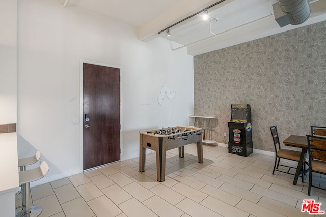 rec room with light tile patterned flooring, beamed ceiling, and rail lighting