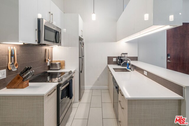 kitchen with stainless steel appliances, white cabinets, sink, decorative light fixtures, and light tile patterned floors