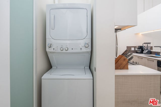 washroom with sink and stacked washer / dryer