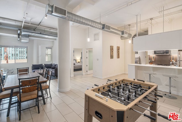 kitchen with white cabinetry, decorative backsplash, light tile patterned floors, and a towering ceiling