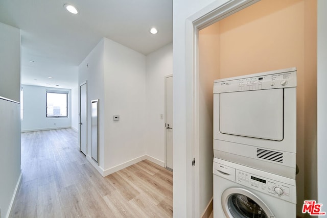 clothes washing area with stacked washer and clothes dryer and light hardwood / wood-style flooring