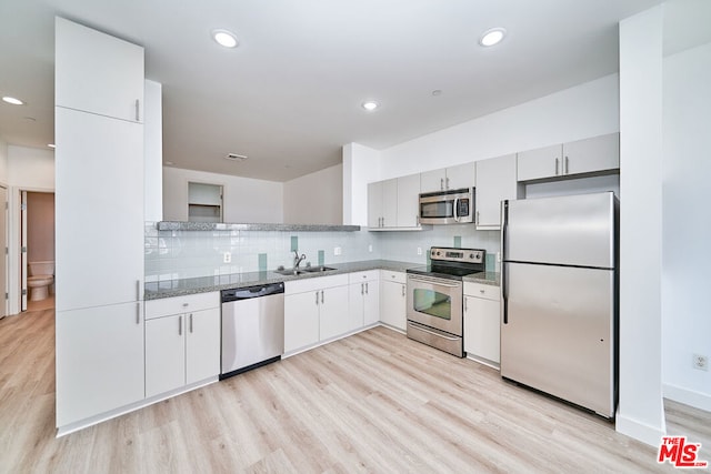 kitchen featuring light hardwood / wood-style floors, sink, decorative backsplash, and stainless steel appliances