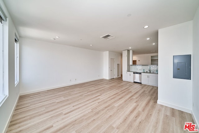 unfurnished living room featuring sink, light hardwood / wood-style floors, and electric panel