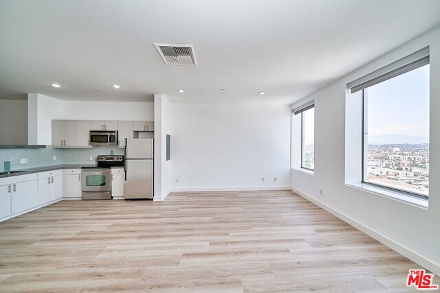 kitchen with stainless steel appliances, gray cabinetry, sink, backsplash, and light hardwood / wood-style floors