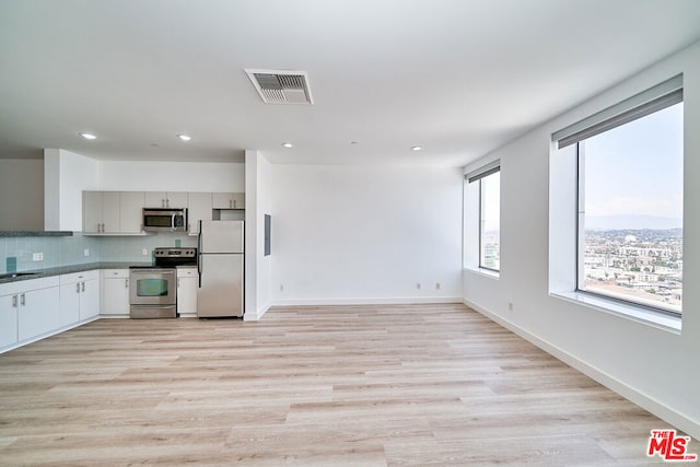 kitchen with tasteful backsplash, stainless steel appliances, sink, and light hardwood / wood-style flooring